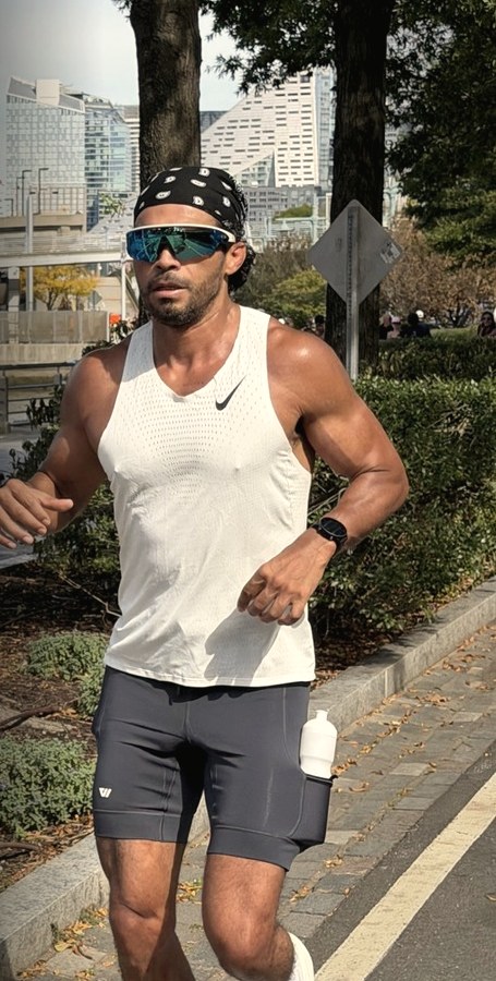 Juan C. Zuniga Jr. running along the waterfront in a white singlet